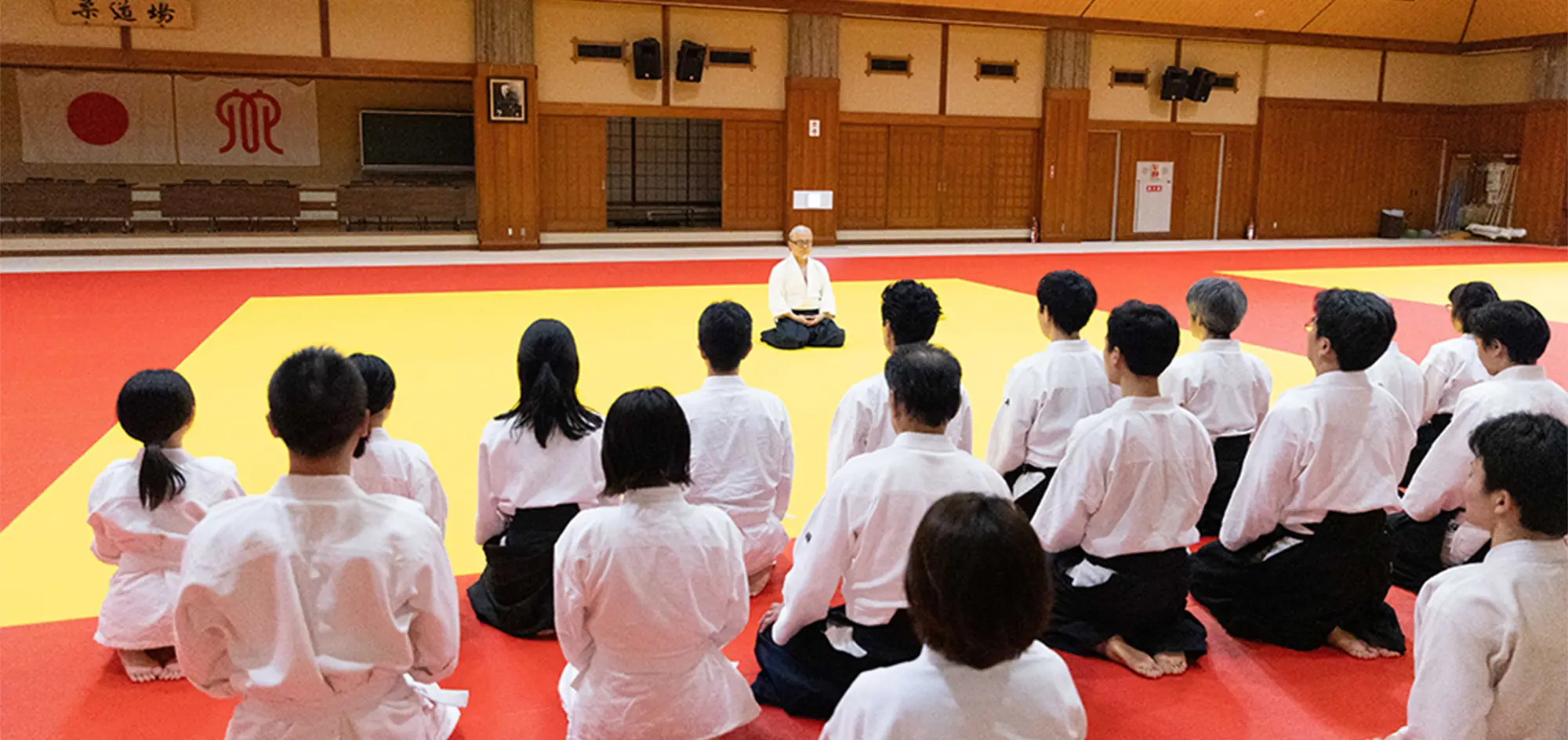 道場で正座し、師範の話を聞く門下生たち